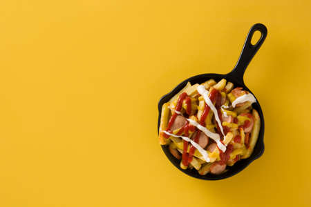Typical Latin America Salchipapa. Sausages with fries, ketchup, mustard and mayo in iron pan and...