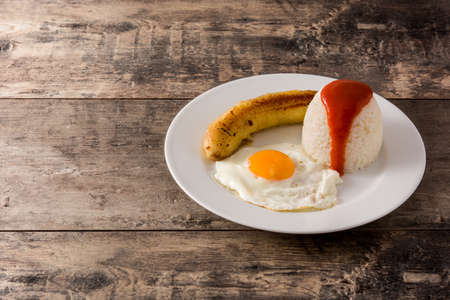 Cuban rice Typical Cuban rice with fried banana and fried egg on a plate on wooden table copy spaceの写真素材