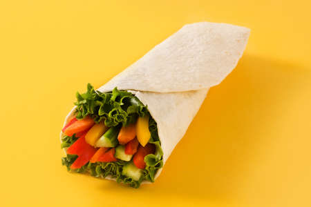 Vegetable tortilla wraps on yellow background