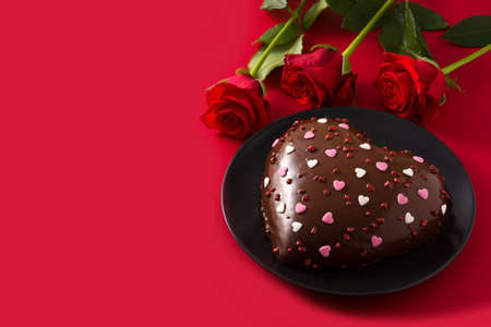 Heart shaped cake and red rose for Valentine's Day or mother's day on red backgroundの写真素材