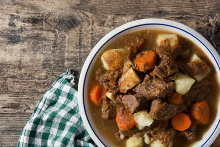 Irish beef stew with carrots and potatoes on wooden table
