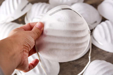 Woman holding a medical face mask on wooden tableの写真素材