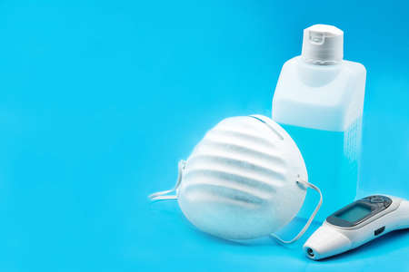 Disinfectant and  face mask on blue background