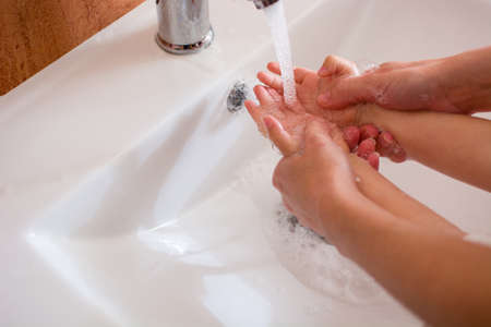 Mother and daughter washing hands in bathroom