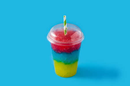 Colorful slushie of differents flavors with straw on blue backgroundの写真素材