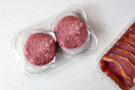 Different types of meat packaged in plastic on wooden table