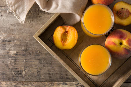 Natural peach juice in glass on wooden tableの写真素材