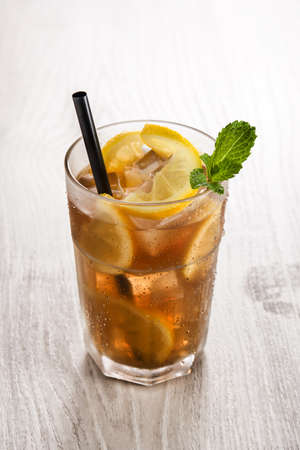 Iced tea drink with lemon in glass on white wooden tableの写真素材