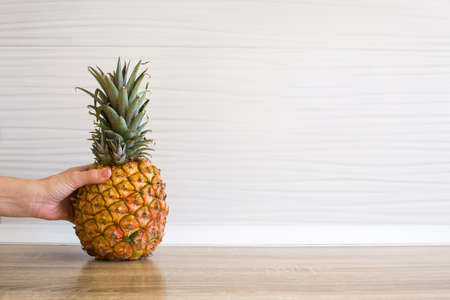 Female hand picking up a pineapple in the kitchenの写真素材