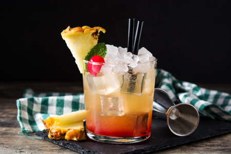 Cold mai tai cocktail with pineapple and cherry on wooden table.の写真素材