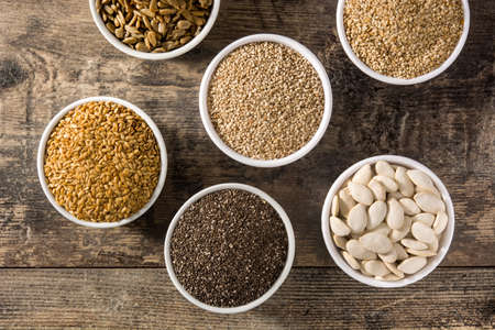 Assortment of different seeds in bowl on wooden table. Pumpkin, linen, chia, sunflower and sesame seeds.の写真素材