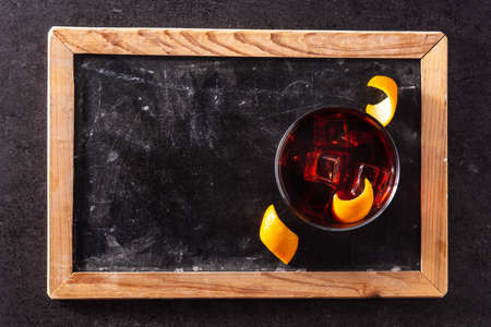 Boulevardier cocktail and orange zest on black slate background