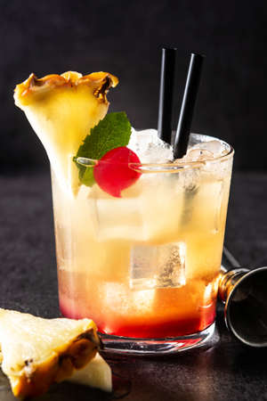 Cold mai tai cocktail in glass on black stone
