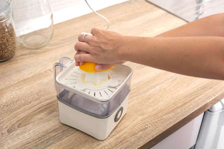 Woman squeezing oranges in the kitchenの写真素材