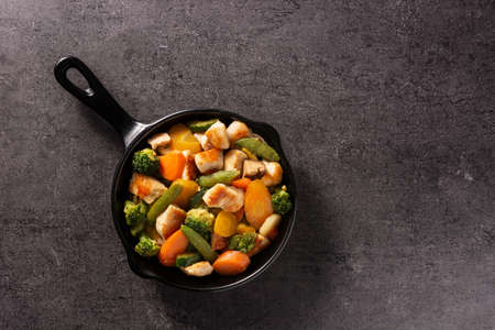 Stir fry chicken with vegetables on iron pan on black backgroundの写真素材