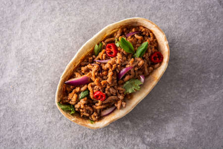 Mexican barquita taco with beef, chilli, tomato, onion and spices on gray stone backgroundの写真素材