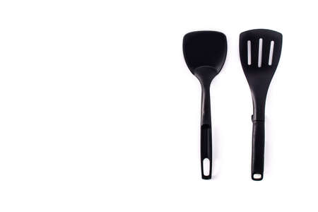 Black plastic kitchen spatula and spoon isolated on white background