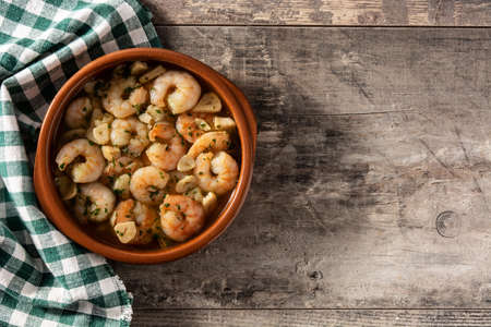 Garlic prawns in crockpot on wooden tableの写真素材