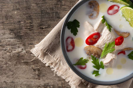 Traditional Thai food Tom Kha Gai in bowl on wooden tableの写真素材