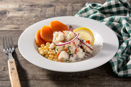 Traditional peruvian ceviche with fish, sweet potato, corn and vegetables on wooden tableの写真素材