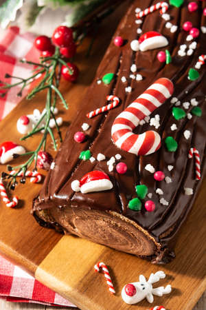 Chocolate yule log christmas cake on wooden tableの写真素材
