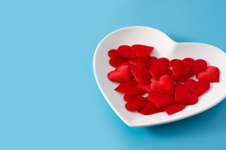 Heart shaped plate with red hearts inside on blue backgroundの写真素材
