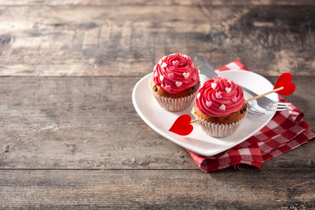 Cupcake decorated with sugar hearts and an arrow for Valentine's Day on wooden tableの写真素材