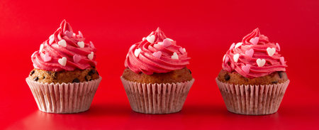 Cupcakes decorated with sugar hearts for Valentine's Day on red backgroundの写真素材