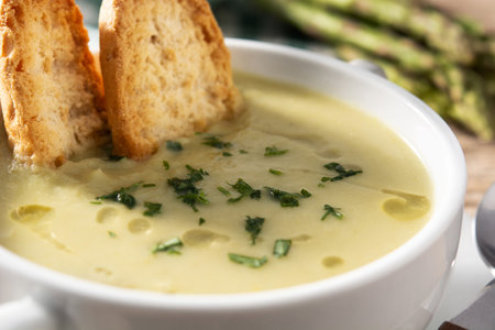 Fresh green asparagus soup in bowl on wooden tableの写真素材