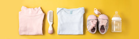 Baby rompers, shoes, feeding bottle, pacifier and hair comb on yellow background.の写真素材