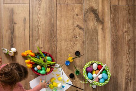 Baby girl painting Easter eggs at homeの写真素材