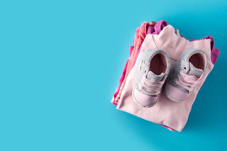 Baby rompers and baby shoes on blue backgroundの写真素材