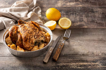 Delivery roasted chicken with potatoes on wooden tableの写真素材