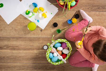 Baby girl painting Easter eggs at home