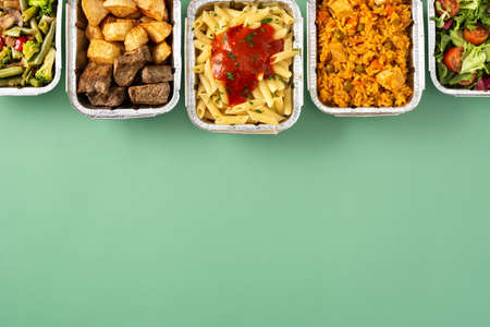 Take away healthy food in foil boxes on green backgroundの写真素材