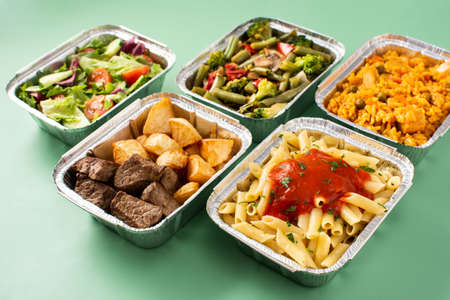 Take away healthy food in foil boxes on green backgroundの写真素材