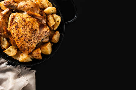 Homemade roasted chicken with potatoes on black slate backgroundの写真素材