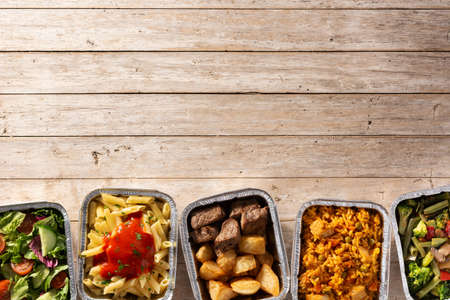Take away healthy food in foil boxes on wooden table