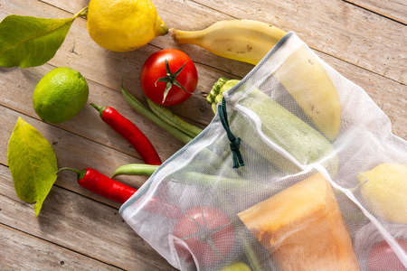 Eco friendly reusable shopping bag with vegetables and fruit on wooden tableの写真素材
