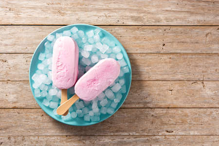 Strawberry ice creams and crushed ice on blue plate and wooden table