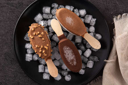 Chocolate ice creams and crushed ice on black background