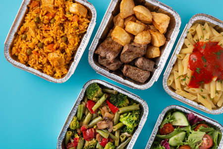 Take away healthy food in foil boxes on blue backgroundの写真素材