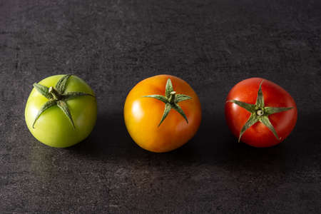 Different color tomatoes on black slate backgroundの写真素材