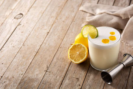 Pisco sour cocktail on wooden table. Traditional peruvian cocktailの写真素材