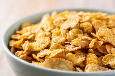 Corn flakes in a blue bowl on wooden table