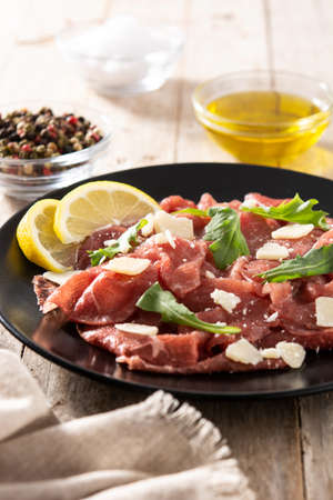 Marbled beef carpaccio on black plate and rustic wooden tableの写真素材