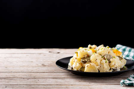 Potato salad with gherkins, egg and mustard on wooden tableの写真素材