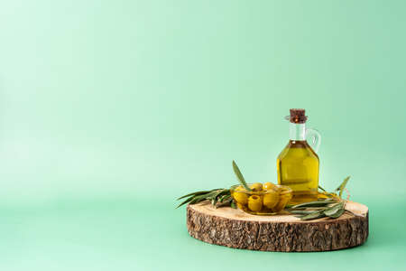 Virgin olive oil bottle and green olives on green backgroundの写真素材