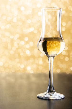 Italian golden grappa drink on brilliant golden backgroundの写真素材