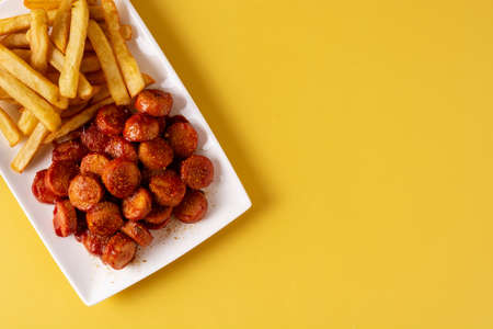Traditional German currywurst on yellow background. Suasages with ketchup and curryの写真素材